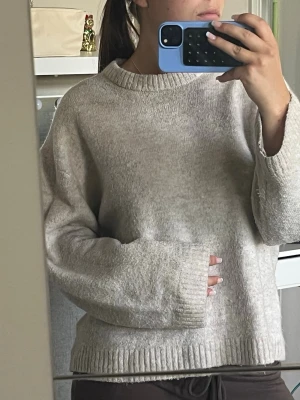 Beige oversized stickad tröja - Mysig beige stickad tröja med oversized passform och rund hals. Tröjan har långa ärmar och ribbade muddar vid ärmslut och nederkant. Perfekt för lager på lager och chill vardagsstil.
