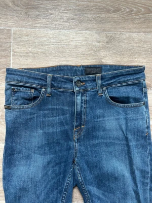 Mörkblå  jeans med stretch - Snygga mörkblå  jeans med klassisk femficksdesign och smal passform. Jeansen har orangea sömmar och är tillverkade i ett stretchigt denimtyg som sitter tajt längs benen. Perfekta för en trendig och avslappnad look.