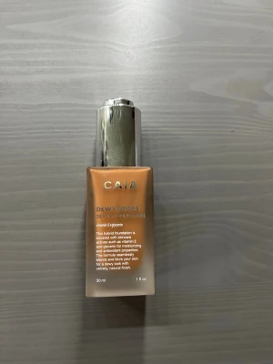 CAIA Dewy Drops Foundation 40N - Foundation från CAIA i nyansen 40N. Köpt förra veckan. Använd endast en gång. Säljer pågrund av att den är för mörk på mig❣️