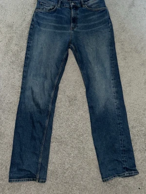 Blå GANT jeans med klassisk tvätt - Säljer ett par blå GANT jeans med rak passform och klassisk tvätt. Jeansen är tillverkade i denim med kontrastsömmar. Perfekta till en casual outfit.