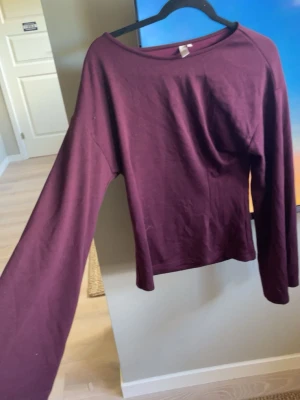 Vinröd långärmad topp - En enkel och stilren vinröd långärmad topp med rund halsringning tajt mage och utsvängda armar. Tillverkad i mjukt bomullsmaterial som känns skönt mot huden. Perfekt att matcha med jeans eller kjol för en avslappnad look.