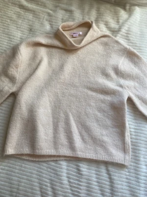 Beige stickad polotröja - Mysig beige stickad polotröja i mjukt material. Tröjan har en avslappnad passform, långa ärmar och ribbade muddar vid ärmslut och nederkant. Perfekt för lager på lager under kyliga dagar.