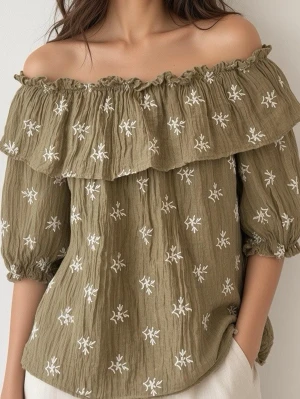 Olivgrön off shoulder blus med broderi - Trendig olivgrön off shoulder-blus med volang upptill och vita broderade blommor över hela plagget. Blusen har trekvartsärmar med resår vid ärmslut och är gjord i ett lätt, krinklat tyg som ger en avslappnad känsla.
