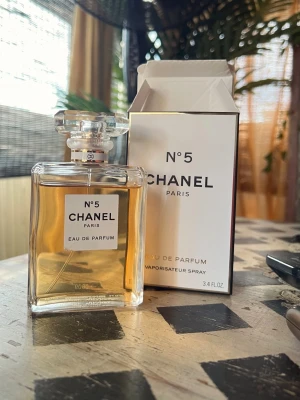 Chanel No 5 edp, 100ml - Klassisk Chanel No 5 Eau de Parfum i elegant, genomskinlig glasflaska med guldtonad vätska och stilren vit etikett. Kommer med originalkartong i vitt med svarta detaljer. En ikonisk doft som andas lyx och tidlöshet.