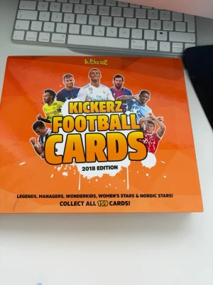 Kickerz Football Cards 2018 album - Säljer ett Kickerz Football Cards samlaralbum från 2018 med flera fotbollskort i plastfickor. Albumet har en orange framsida med bilder på kända spelare och texten 'Collect all 159 cards!'. Perfekt för dig som gillar fotboll och samlarkort.