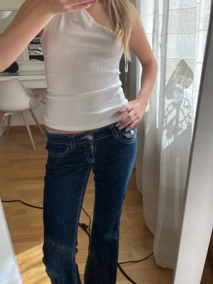 Mörkblå bootcut jeans med kontrastsömmar - Säljer ett par mörkblå bootcut jeans med vita kontrastsömmar och klassiska fem fickor. Säljer pga de är små använd 2-3 gånger annars nästan helt nya. 