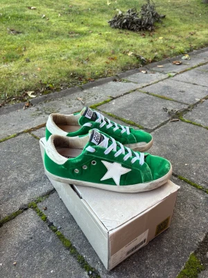 Gröna golden goose - Snygga gröna sneakers med vit stjärndetalj på sidan och vita skosnören. Skorna har låg profil och vit sula. Materialet ser ut att vara mocka eller liknande tyg. Perfekta för dig som vill sticka ut med färg på fötterna.