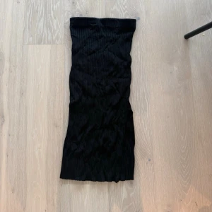 Svart ribbad långkjol - Säljer en svart långkjol med ribbad struktur. Kjolen har en rak och smal passform som ger en stilren look. Perfekt att matcha med en crop top eller oversized tröja för en trendig outfit.
