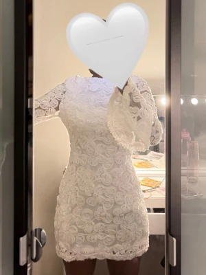 Vit spetsklänning med vida ärmar (NY MED PRISSLAP) - Supersnygg vit klänning i spets med blommigt mönster och figurnära passform. Klänningen har långa, vida ärmar och rund halsringning. Perfekt för dig som vill sticka ut med en romantisk och trendig look. Materialet är genombruten spets som ger en elegant känsla. Funkar perfekt till resor, STUDENT osv. Ny pris 600 kr
