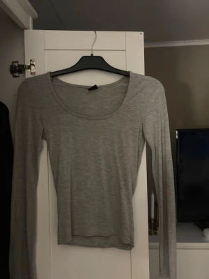 Ljusgrå långärmad topp - En enkel och stilren ljusgrå långärmad topp med rund halsringning. Tillverkad i ett mjukt och stretchigt material som sitter skönt på kroppen. Perfekt att matcha med jeans eller kjol för en clean look. Även en liten ”slits” vid ärmarna💕