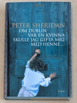 Om Dublin var en kvinna... - Roman av Peter Sheridan med ett blått omslag som visar ett barn i vit skjorta framför en stor dörr. Bokens titel och författare är tryckta i guld och vitt. Utgiven av Forum förlag. Perfekt för dig som gillar berättelser med starka miljöskildringar.