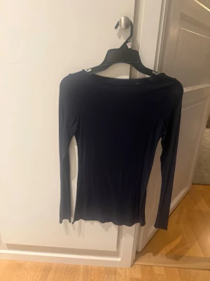 Intimissimi tröja - En enkel och stilren marinblå långärmad topp med rund hals. Perfekt att matcha med jeans eller kjol för en clean look. Materialet känns mjukt och stretchigt, vilket gör den bekväm att bära hela dagen.