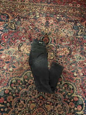 Grå Dondup Jeans - Säljer ett par mörkgrå jeans från Dondup med klassisk femficksdesign och en smal/slim passform. Jeansen har en enkel bakficka utan synlig logga och är tillverkade i stretchigt denimtyg som sitter snyggt. Perfekta till en avslappnad och trendig look. 💫
