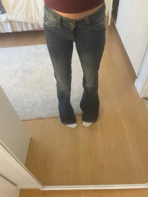 Marinblå cheap monday jeans  - Säljer ett par mörkblå bootcut jeans med snygga lätt utsvängda ben. Jeansen har klassisk femficksdesign och stängs med knapp och dragkedja. Perfekta för dig som gillar en retroinspirerad look.