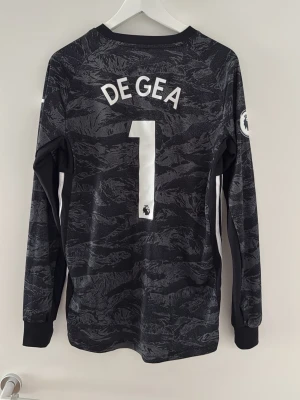 Manchester United målvaktströja 2019/20 - Säljer en svart långärmad Manchester United målvaktströja från Adidas med De Gea och nummer 1 på ryggen. Tröjan har Premier League badge på ärmen. Tröjan är stor i storleken och passar nästan mig som är 185 cm. Köpte den från Unisport för 1200kr och säljer den för 700kr då den är som ny. Pris kan diskuteras också👍// Viktor
