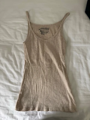 Beige ribbad linnetopp  - Säljer en beige ribbad linnetopp från Esmara. Toppen har smala axelband och en figurnära passform. 