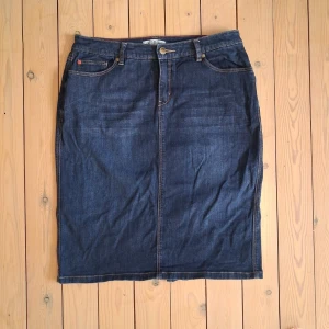 Hampton Republic Mörkblå Jeanskjol - Snygg mörkblå jeanskjol från Hampton Republic. Kjolen har normal midja och en öppning på baksidan för ökad rörlighet. Midja ca  82 cm (ca 41 cm rakt över). Längd ca ca 61 cm.