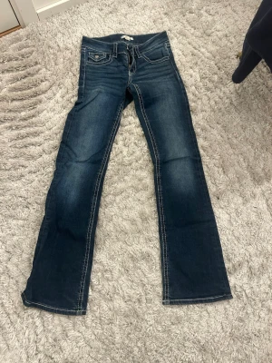 Mörkblå bootcut jeans Gina Tricot - Snygga mörkblå bootcut jeans från Gina Tricot med kontrastsömmar och klassisk femficksmodell. Jeansen har dragkedjegylf och knapp framtill. Perfekta för dig som gillar en tidlös och avslappnad stil.