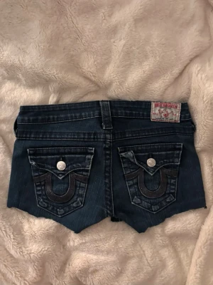 Mörkblå jeansshorts true religion  - Egen avklippta super lågmidjade jeans shorts från true religion med snygga detaljer! Stl 26 o fint skick!