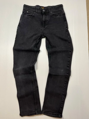 Lee jeans – svarta – barn 12–13 år – bra skick - Säljer ett par svarta Lee-jeans i storlek 12–13 år för barn/kille. Mycket bra skick. En klassisk modell som funkar till vardags.  • Skick: Mycket bra • Storlek: 12–13 år • Kön: Barn / Kille • Färg: Svart • Märke: Lee