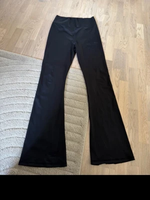 Svarta utsvängda leggings Aim'n - Säljer ett par svarta leggings från Aim'n med utsvängda ben och hög midja. Tillverkade i stretchigt material som sitter skönt och följer kroppen. Diskret logga på låret. Perfekta för en trendig och bekväm look. Något sönder nere vid foten då dom är ganska långa, jag är 178 cm.