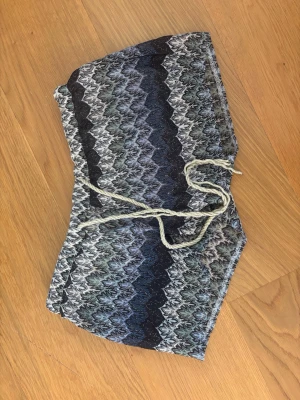 Mönstrade shorts  - Säljer en snygg bandeau bikini med zigzagmönster i svart, grått och blått. Shortsen har snörning i midjan och en unik struktur i materialet. Perfekt för sommaren 