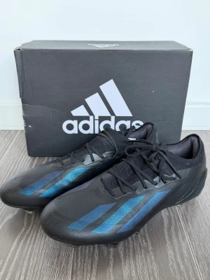 Adidas fotbollsskor  - Snygga fotbollsskor från Adidas i svart med blå metallicfärgade ränder på sidorna. Använda ett fåtal gånger. Storlek 42. Pris kan diskuteras vid snabb affär. Nypris 1800kr
