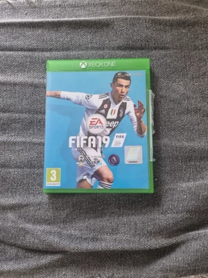 FIFA 19 till Xbox One - FIFA 19 är ett fotbollsspel till Xbox One med en grön plastfodral och blå framsida. Spelet är utvecklat av EA Sports och har en omslagsbild med en fotbollsspelare i Juventus tröja. Perfekt för dig som gillar sportspel och fotboll.