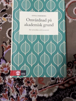 Omvårdnad på akademisk grund - Boken 'Omvårdnad på akademisk grund' av Anna Forsberg har ett grönt och vitt omslag med bladmotiv. Perfekt som kurslitteratur för dig som pluggar vård eller omvårdnad på högskola eller universitet.