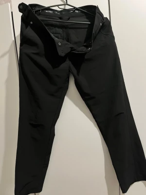 Svarta slim fit jeans - Säljer ett par svarta slim fit jeans med klassisk femficksdesign och knappgylf. Jeansen har en stilren look och passar perfekt till en trendig vardagsstil. Materialet känns mjukt och stretchigt för extra komfort.