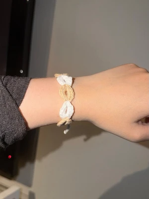 Handvirkad armband  - Unikt armband i beige och vitt med handknutna pärldetaljer. Armbandet är gjort av snöre och har en bohemisk känsla med flätad design. 30cm lång. Önskas custom, kontakta mig!
