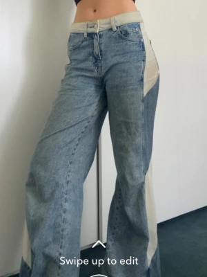 Blå jeans med ränder  - Trendiga blå jeans med bred passform och unika ränder längs sidorna och bak. Midwaist midja och klassisk femficksdesign. Jeansen har en cool patchwork-look och är tillverkade i denim, perfekt för dig som gillar en modern och edgy stil.