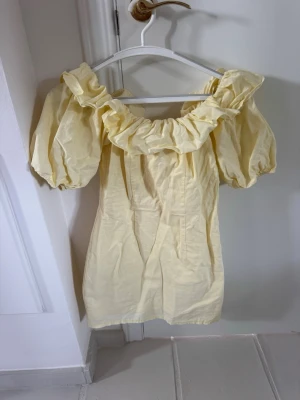 Gul kort klänning från H&M - Söt gul kort klänning från H&M med puffärmar och bred volang runt axlarna. Jätte populär och går inte att få tag på längre💛