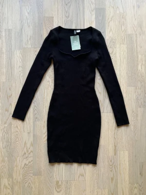 H&M Divided klänning – S – Ny med prislapp - Ny med prislapp  Klänning från H&M Divided, storlek S, svart Ribbad, långärmad klänning. Figurnära passform med stretchigt tyg. Fyrkantig ringning med litet V.  Polyester, polyamid, viskos Inga defekter