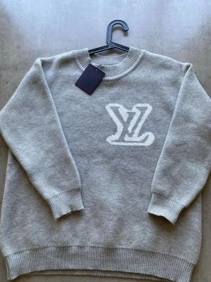 Hoodie - Grå stickad tröja med en logga på 