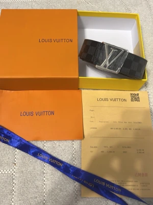 L och V rutigt svart bälte - Säljer ett L och V bälte i svart med rutigt mönster och stor silverfärgad -spänne. Bältet kommer med originalbox, dustbag och kvitto. Perfekt accessoar för att lyfta din outfit.
