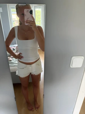 Vita fransiga jeansshorts - Säljer en fin vit topp men öppen rygg och knut . Perfekt för varma sommardagar och ger en fräsch look till din outfit.