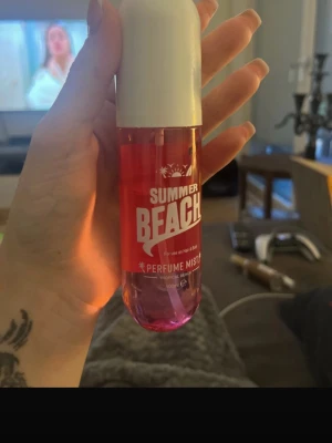 Summer Beach Perfume Mist rosa - Fräsch parfymmist med namnet Summer Beach i en cylinderformad plastflaska. Flaskan är rosa med vit kork och rymmer 100 ml. Passar både hår och kropp och har en somrig, lätt känsla. Perfekt för dig som vill ha en fräsch doft till vardags.