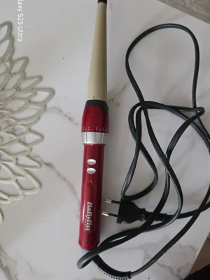Röd locktång från BaByliss - Säljer en röd och beige locktång från BaByliss med konisk form och sladd med EU-kontakt. Perfekt för att fixa snygga lockar snabbt. Två knappar på handtaget för enkel användning.
