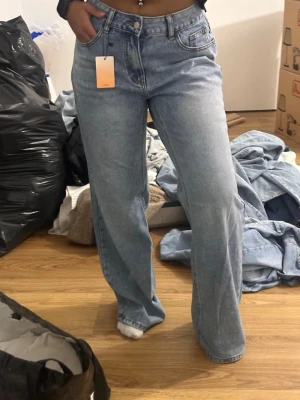 Ljusblåa raka jeans med hög midja - Säljer ett par ljusblå jeans med rak passform och hög midja. Jeansen har klassiska fem fickor, bälteshällor och stängs med knapp och dragkedja. Materialet är denim i bomull och de har en avslappnad, trendig look. Storlek 25 forever 21