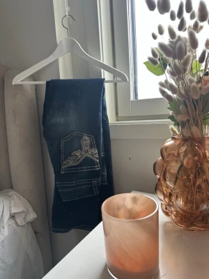 Mörkblå jeans med broderad ficka - Säljer ett par mörkblå jeans med snyggt broderi på bakfickan. Jeansen har raka ben och kontrastsömmar som ger en cool look. Köpt på gina tricot Young. Storlek 164. Låg/mellan midja. Säljer pga att dem är för småa för mig💕. 