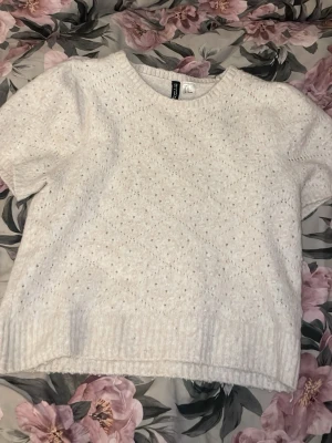Vit stickad tröja från H&M Divided - Säljer en vit stickad tröja från H&M Divided i storlek M.  Skulle säga att den även passar storlek S då det är min vanliga storlek. Tröjan har korta puffärmar, rund halsringning och ett diskret hålmönster. Ribbstickade muddar vid ärmslut och nederkant ger en snygg finish. Perfekt för en trendig och mysig look.