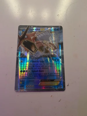 Gyarados EX Pokémonkort holo - Säljer ett Gyarados EX Pokémonkort med holografisk yta. Kortet har blå och silverfärgade detaljer och visar Gyarados i en actionfylld pose. Perfekt för samlare eller Pokémonfans som vill utöka sin kortsamling.