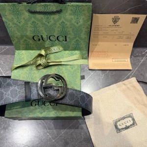 Svart GG Supreme bälte från Gucci - Säljer ett svart GG Supreme bälte från Gucci med det klassiska GG-mönstret och en stor, rund metallspänne med GG-logga. Bältet är gjort i skinn och har en mörk, elegant look. Perfekt accessoar för att lyfta vilken outfit som helst.