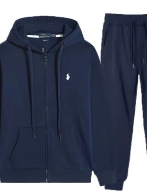 Mörkblå loungewear-set med hoodie - Mörkblått loungewear-set från Polo Ralph Lauren med zip-hoodie och matchande byxor. Hoodien har dragsko, fickor och en liten vit logga på bröstet. Byxorna har resår i midjan och dragsko för skön passform. Perfekt för chill dagar hemma.