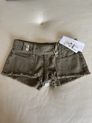 Gröna lågmidjade jeansshorts från Gina - Snygga gröna lågmidjade jeansshorts med fransig, rå kant och dubbla knappar fram. Shortsen har stora fickor både fram och bak samt bälteshällor. Helt nya med prislapp!💞
