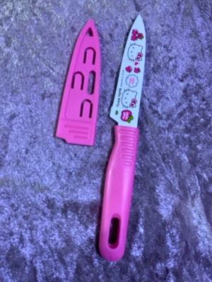 Hello Kitty rosa kniv med skydd - Söt kökskniv med rosa handtag och matchande skydd. Bladet har Hello Kitty-motiv och små jordgubbar tryckta på framsidan. Handtaget är i plast och bladet i metall. Perfekt för dig som gillar gulliga köksprylar. Finns fler kvar 