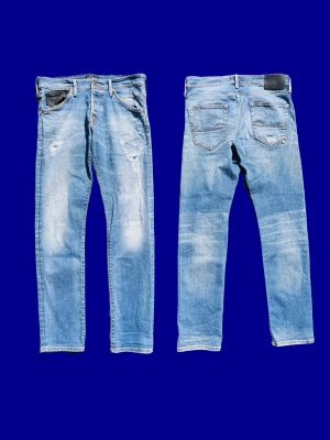 Jack & Jones jeans blå - Säljer ett par ljusblå Jack & Jones jeans med slitningar och raka ben. Jeansen har klassisk femficksmodell, diskreta slitdetaljer framtill och normal midja. Perfekta för en avslappnad och trendig look.