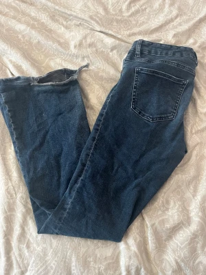 Mörkblå bootcut jeans - Säljer ett par mörkblå bootcut jeans med rå, fransig kant nedtill. Jeansen har klassisk femficksmodell och normal midja. Perfekta för dig som gillar en avslappnad och trendig look. Väl använda jeans🌸