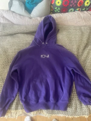 Lila hoodie från Polar Skate Co - Säljer en lila hoodie från Polar Skate Co med vit logga broderad på bröstet. Hoodien har stor huva, magficka och ribbade muddar vid ärmar och midja. Perfekt för dig som gillar streetwear och vill ha en skön och stilren look.